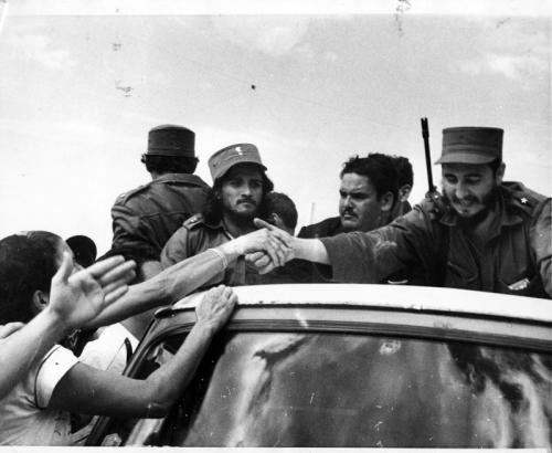 FIDEL SALUDA A UN ADMIRADOR MIENTRAS LA INMENSA MULTITUD RODEA EL AUTO QUE LO CONDUCE DEL AEROPUERTO DE MAIQUETÍA A CARACAS FOTO UPI, 23 DE ENERO DE 1959.